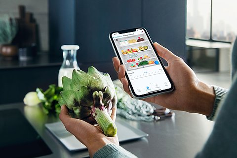 Smartphone wird ins Bild gehalten auf Lebensmittel