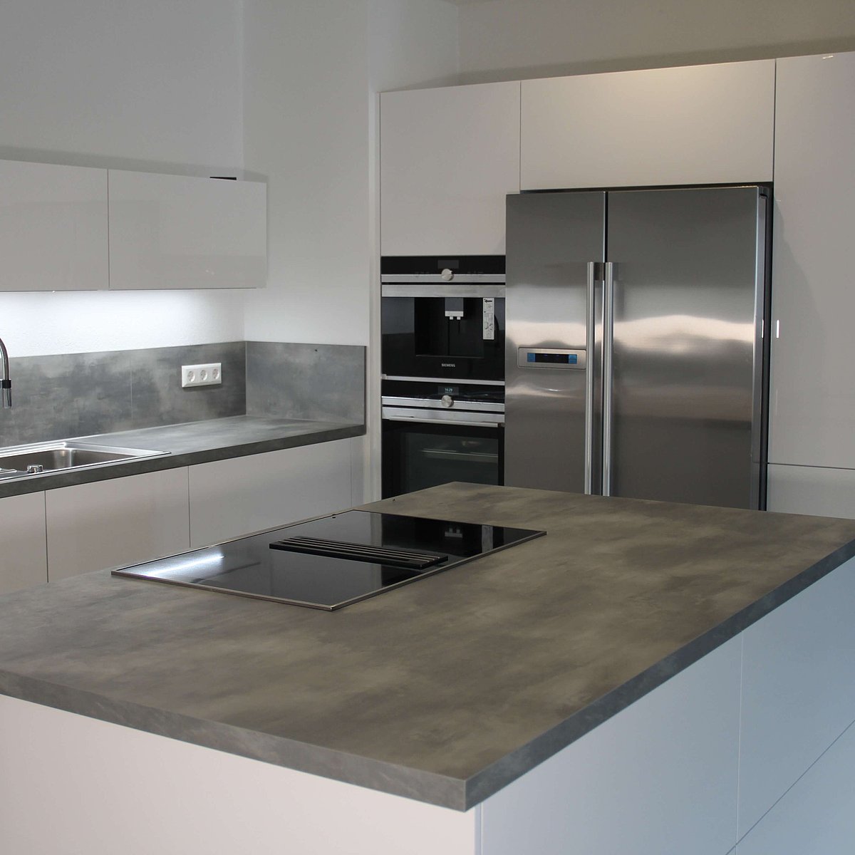 Küche in L Form mit grauer Kunststein ARbeitsplatte und Kochinsel