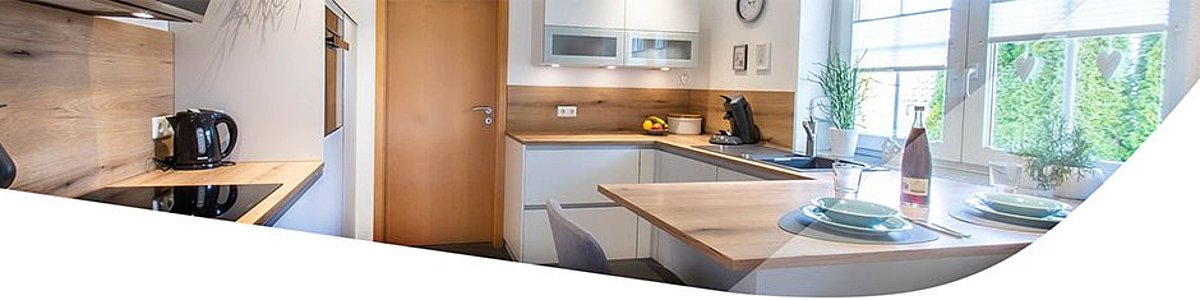 Moderne Einbauküche in weiß mit eichefarbener Arbeitsplatte.