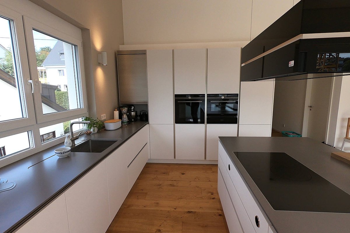 Küche mit Kochinsel Blick auf Backofen und Stauraum in weißer Korpusfront