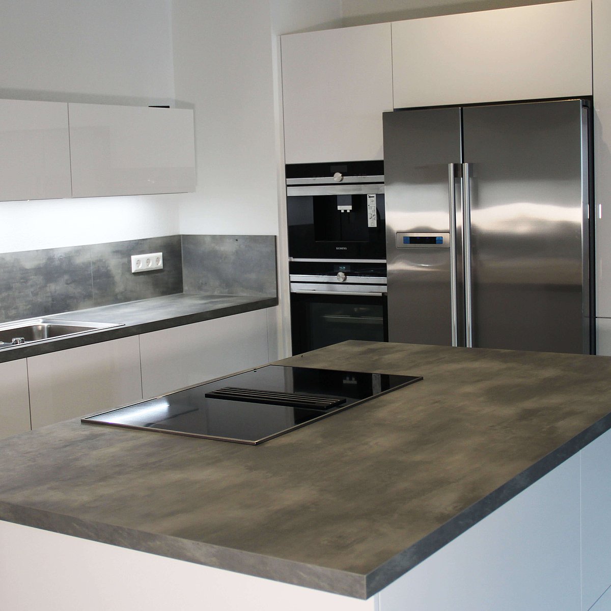 Küche in L Form mit grauer Kunststein ARbeitsplatte und Kochinsel